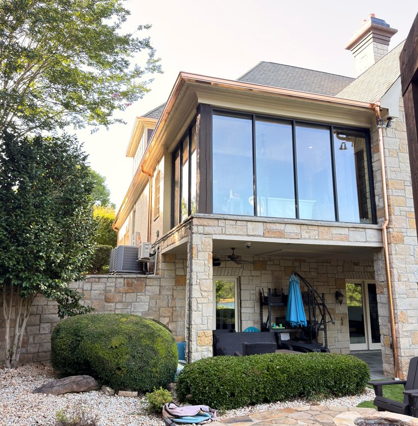 Copper gutter installed on a stone lake house with a glass sunroom